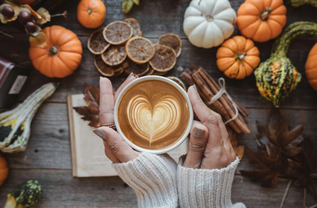 Pumpkin spice latte met kaneel naast een kleine pompoen