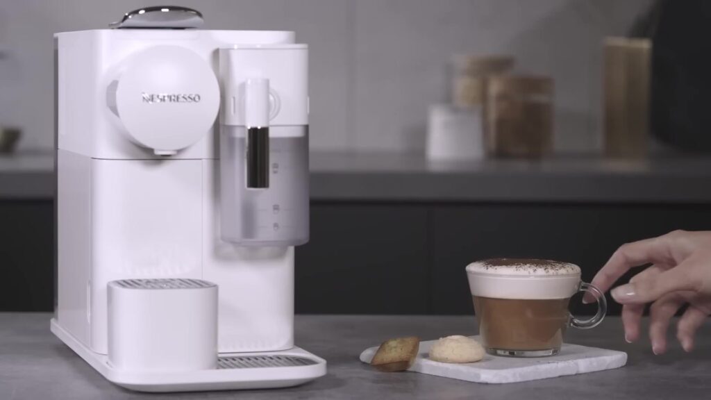 Witte Nespresso Lattissima One met een cappuccino ernaast op het aanrecht