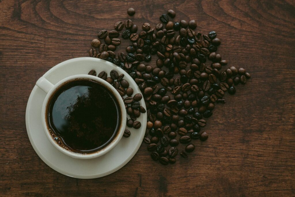 Kop zwarte koffie met losse koffiebonen op een houten tafel