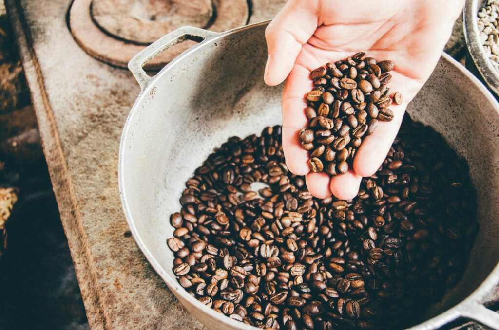Hand vol gebrande koffiebonen boven een zak