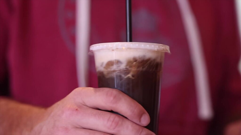 Glas ijskoffie met een dikke laag koud melkschuim erop