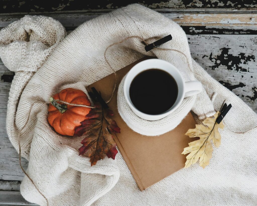 Kop koffie bij een raam met herfstlicht en bladeren buiten