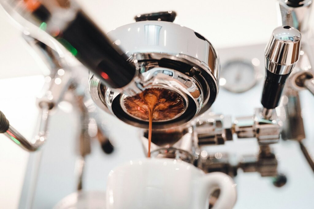 Portafilter met filtermandje en gemalen koffie naast een espressomachine