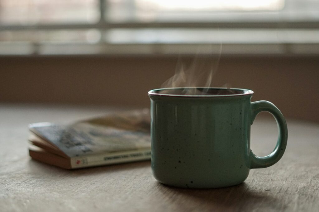 Dampende kop zwarte koffie op een houten tafel in warm keukenlicht