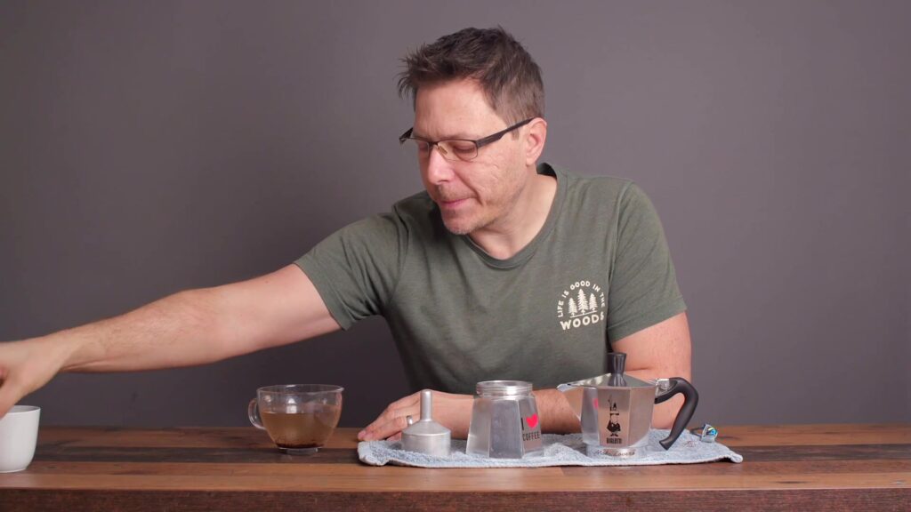 Onderdelen van een aluminium mokkapot van Bialetti naast elkaar op een houten tafel