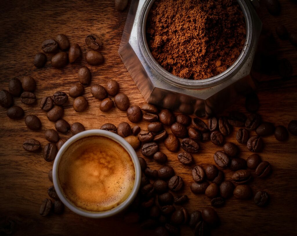 Koffiemolen met versgemalen koffie naast hele bonen op het aanrecht