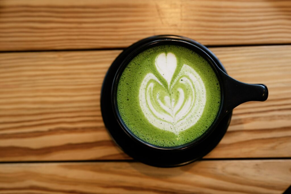 Een matcha latte en een kop koffie naast elkaar op een tafel