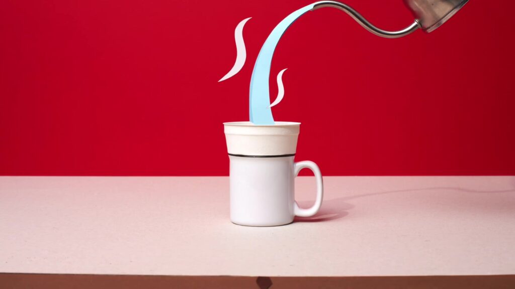 Individuele koffiefilter van Rombouts op een witte mok terwijl er heet water in wordt geschonken