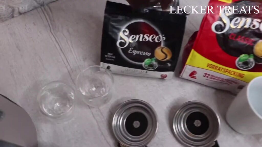 Zakken Senseo koffiepads naast twee padhouders en glazen kopjes